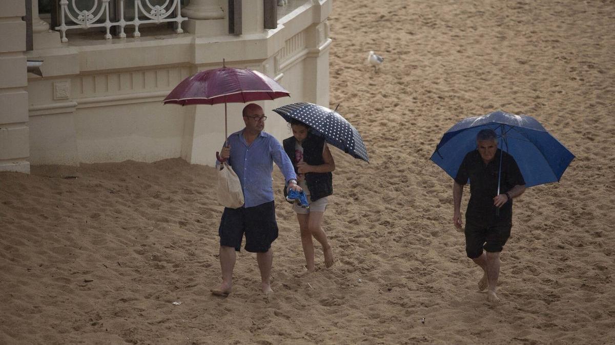 Varias personas se cubren de la lluvia en un día de calor.