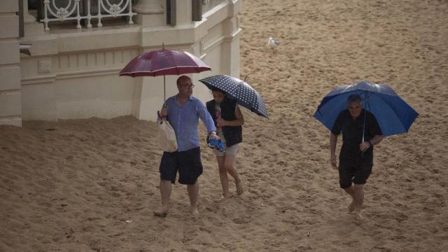 Varias personas se cubren de la lluvia en un día de calor. / Esti Veintemillas Varias personas se cubren de la lluvia en un día de calor.