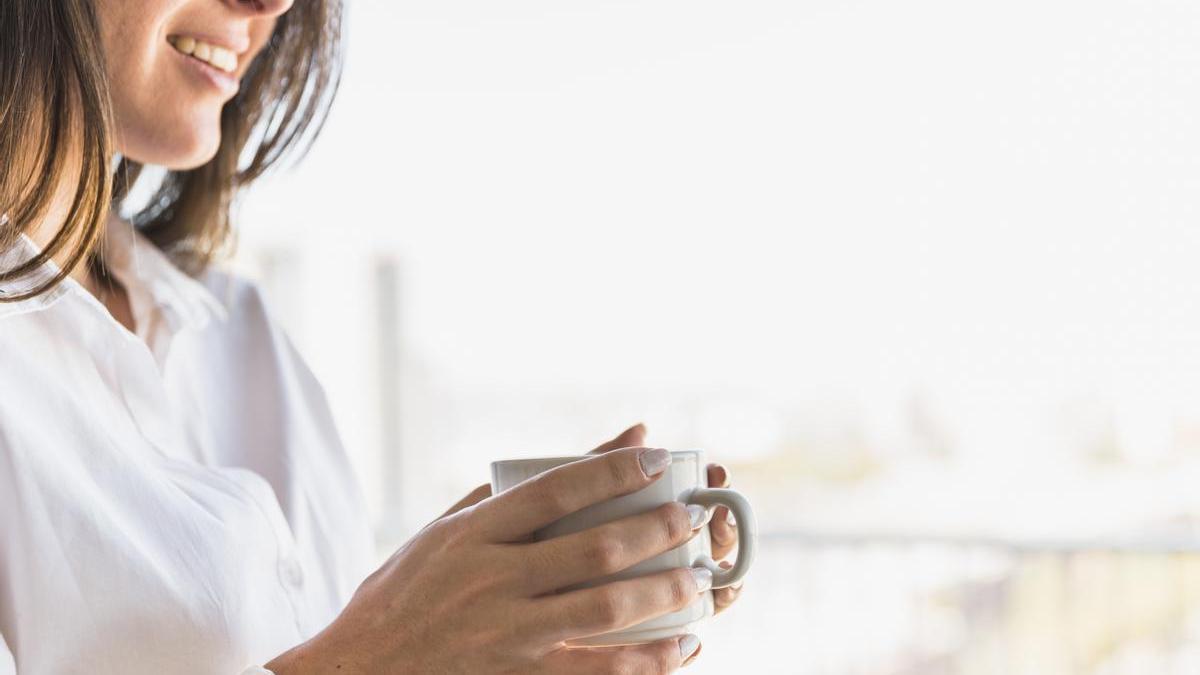 Chica sonríe con una taza de café en las manos