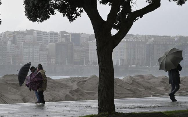 Varias personas se protegen de la lluvia junto a la costa de A Coruña este miércoles.