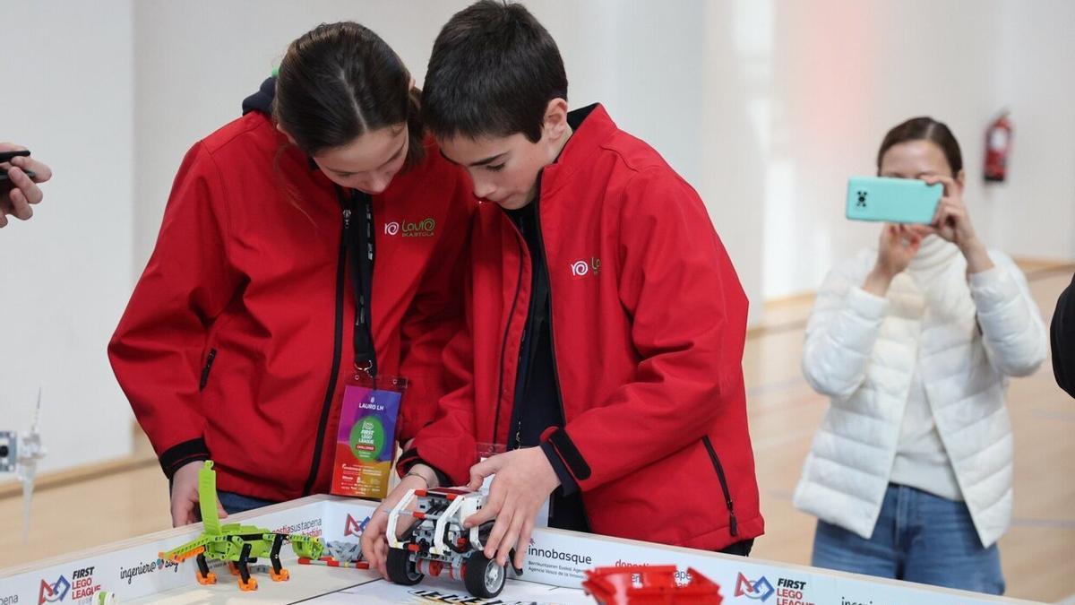 Dos alumnos participantes en la First Lego League dan los últimos retoques al robot.