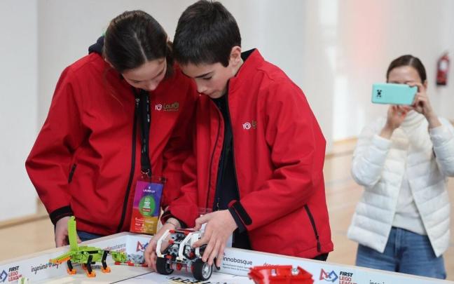 Dos alumnos participantes en la First Lego League dan los últimos retoques al robot.
