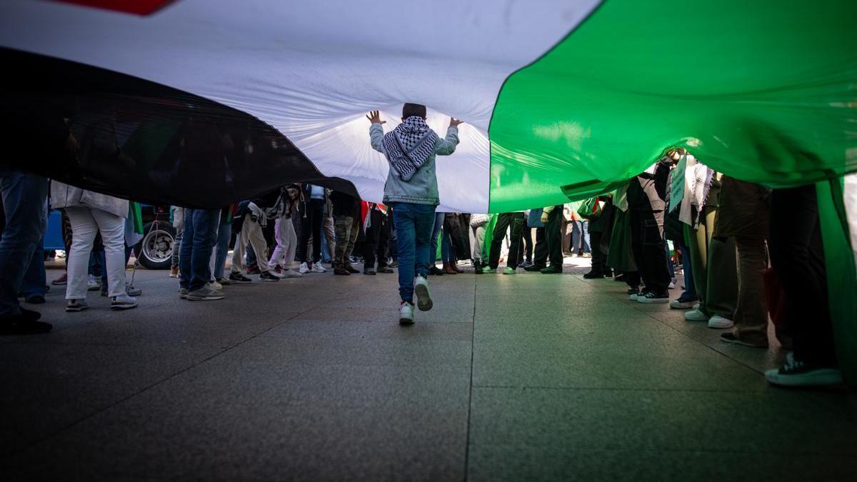 Un menor pasea bajo una bandera palestina durante una protesta en Madrid.