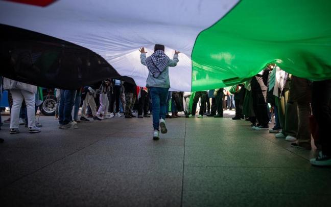 Un menor pasea bajo una bandera palestina durante una protesta en Madrid.