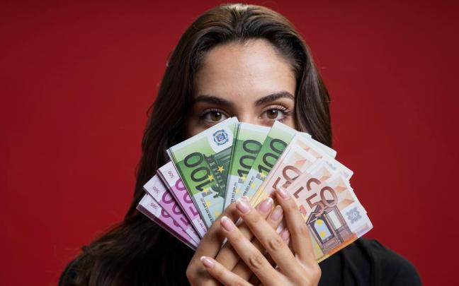 Una mujer sostiene en sus manos billetes de euro de distinto valor. Una mujer sostiene en sus manos billetes de euro de distinto valor.