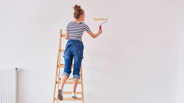 Una mujer pintando su casa