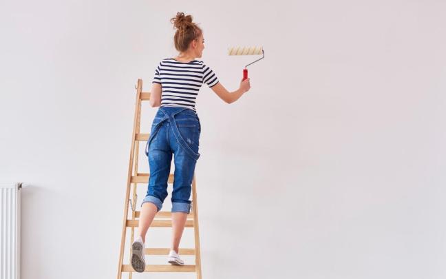 Una mujer pintando su casa