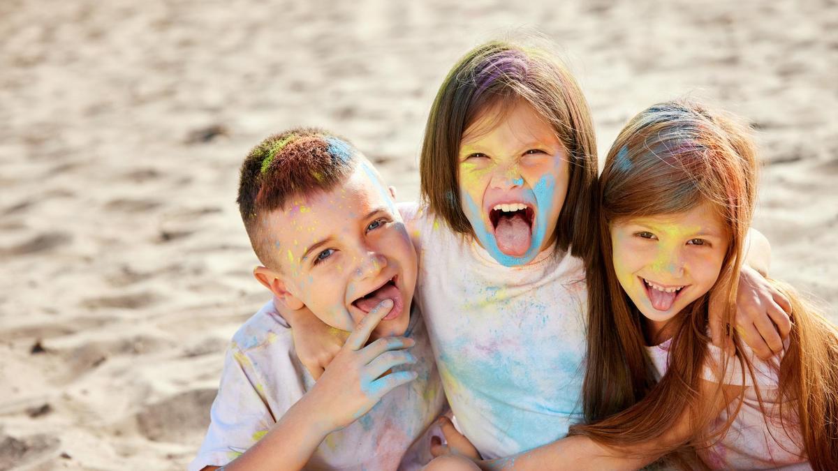 Tres niños posan divertidos en la playa.