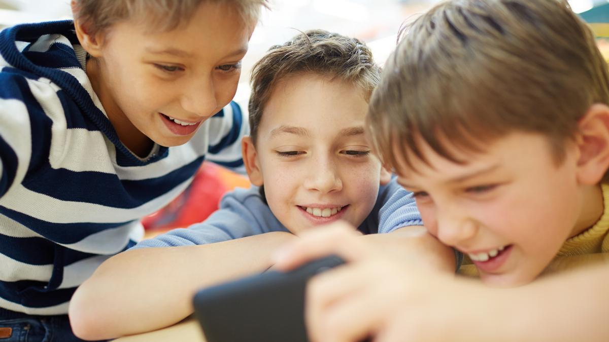 Tres niños observan un vídeo en el teléfono móvil.