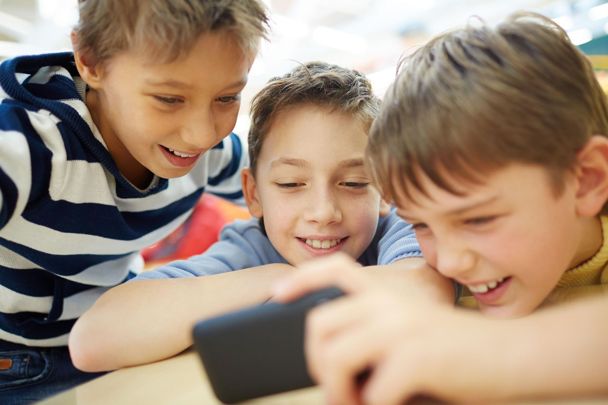 Tres niños observan un vídeo en el teléfono móvil.