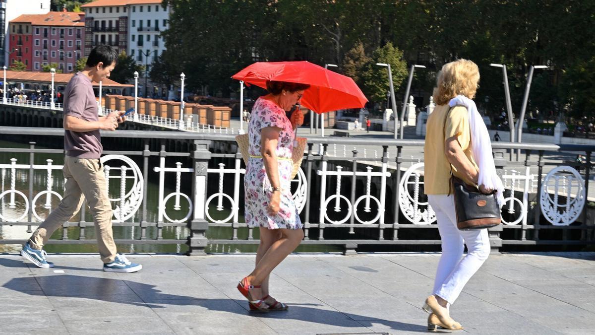 Una mujer se protege con un paraguas del sol.