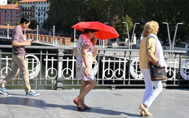 Una mujer se protege con un paraguas del sol. / Oskar Gonzalez Una mujer se protege con un paraguas del sol.