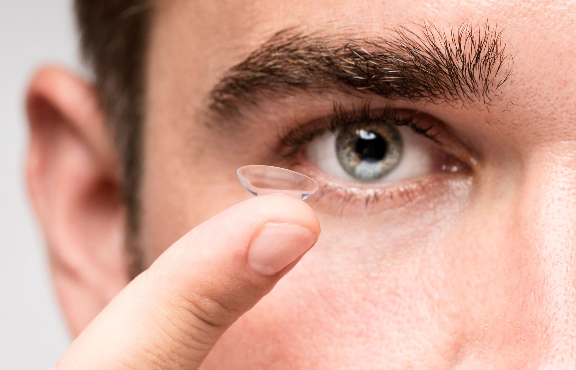 Un hombre a punto de colocarse una lentilla en el ojo.
