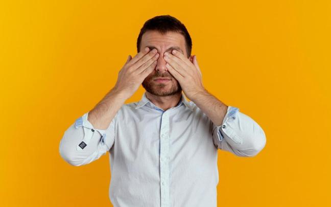 Un hombre se frota los ojos con las manos.