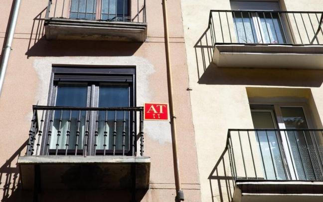 Imagen de un cartel de apartamentos turísticos en un bloque viviendas.