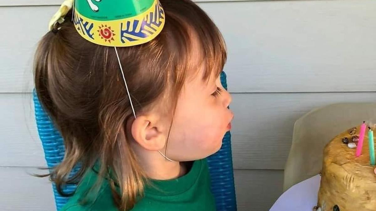 La niña, soplando las velas de la tarta.