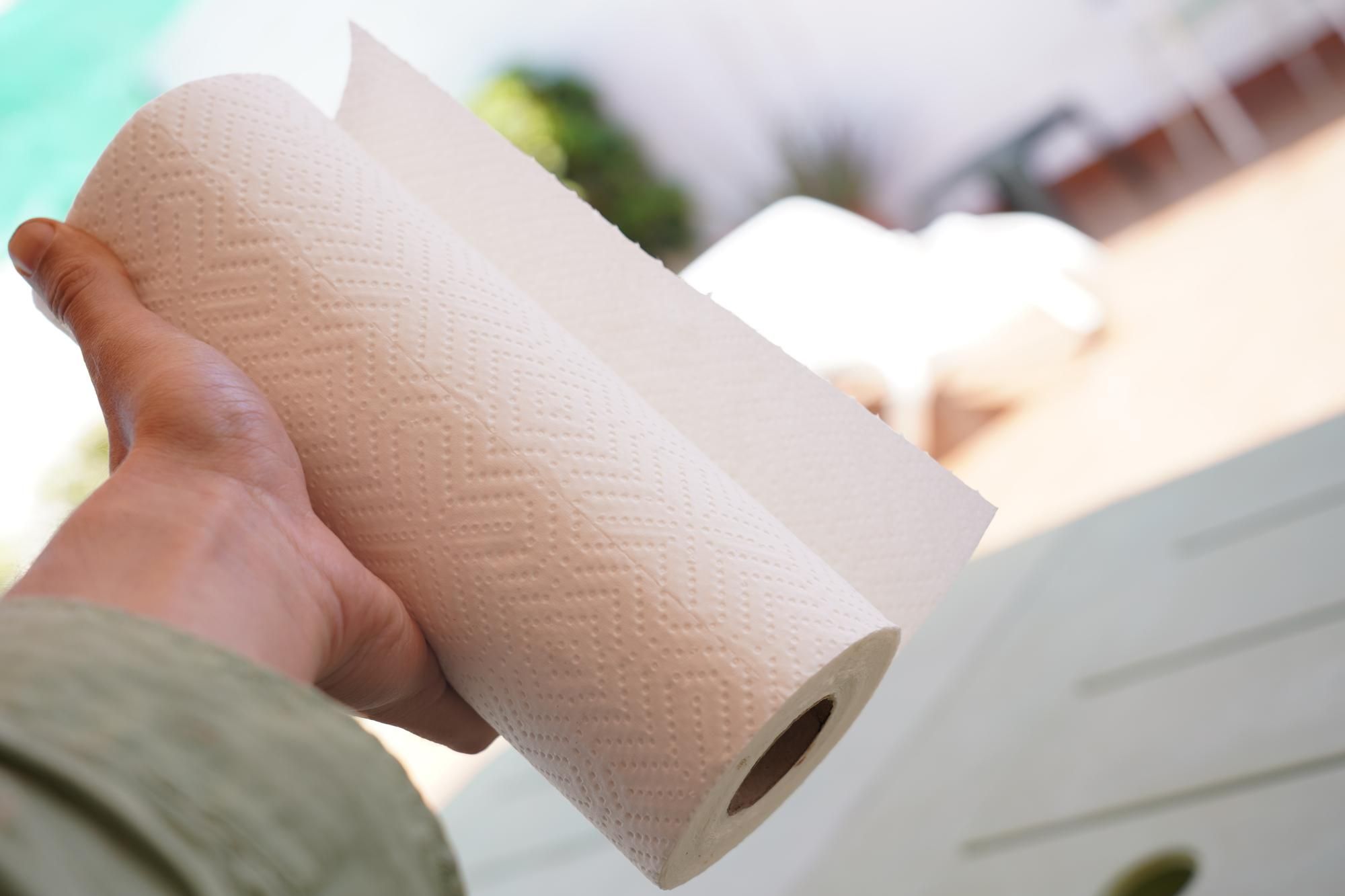 Un hombre sujeta con la mano un rollo de papel de cocina.