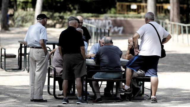 Varios pensionistas juegan al dominó en un parque.