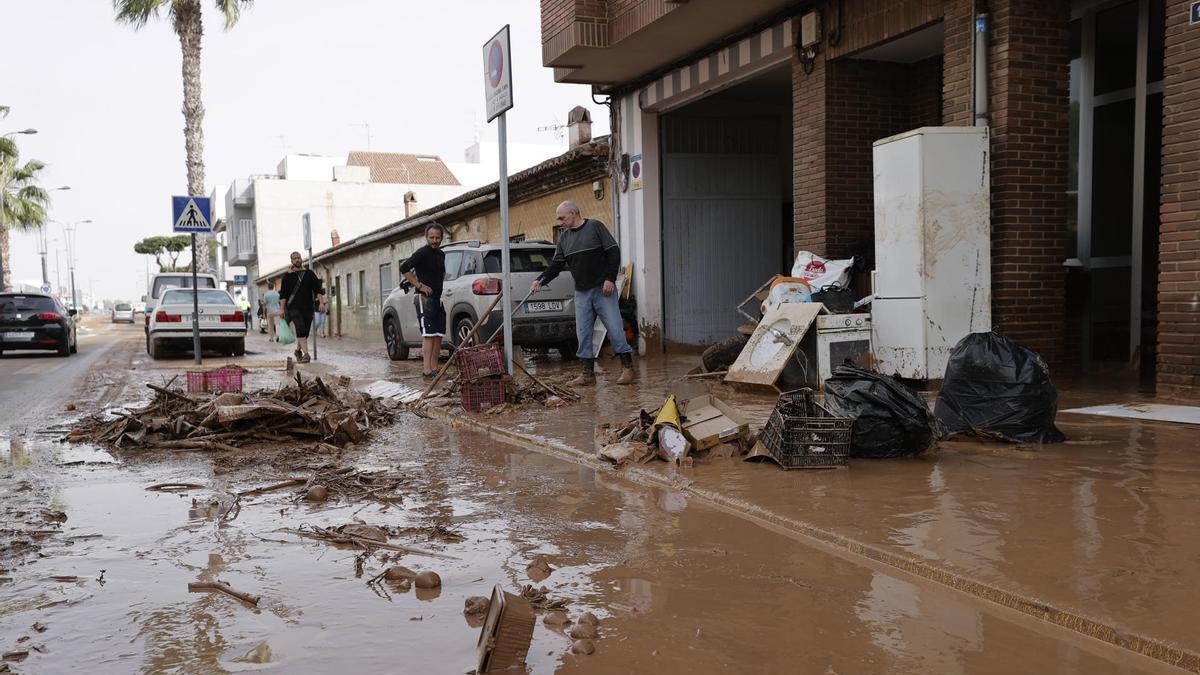 Varias personas limpian el lodo acumulado en sus viviendas a causa de las intensas lluvias en Valencia.