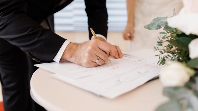 Una pareja firma documentos oficiales de matrimonio.