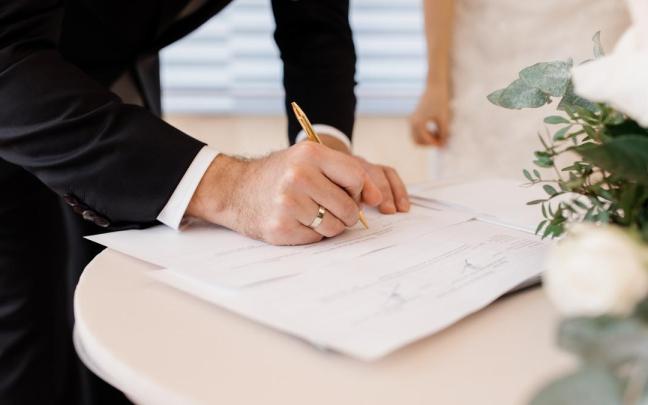 Una pareja firma documentos oficiales de matrimonio.