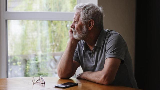 Señor mirando por la ventana con signos de apatía.