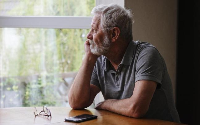 Señor mirando por la ventana con signos de apatía.