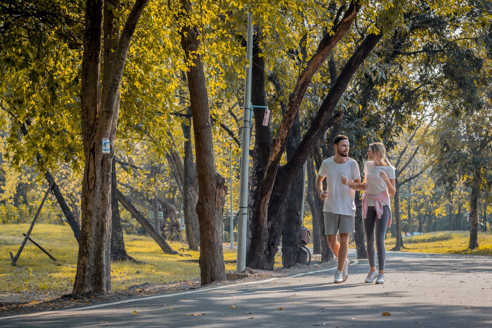 Una pareja camina a paso ligero por un parque.