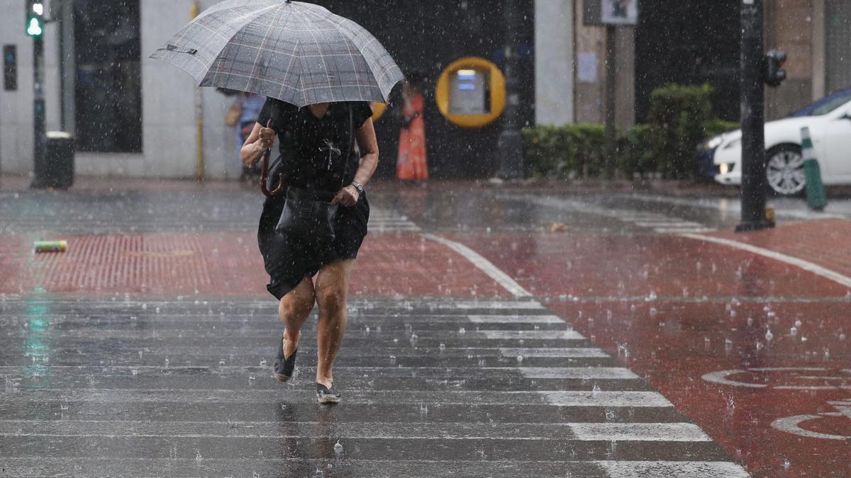 Una mujer camina bajo la intensa lluvia