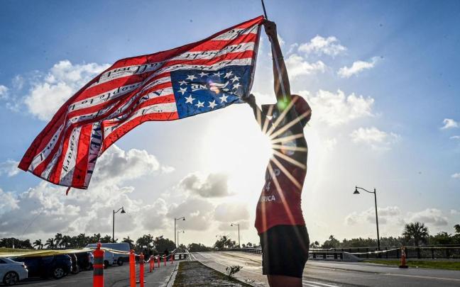Un seguidor de Trump ondea la bandera de Estados Unidos ante la mansión del expresidente en Mar-a-Lago.