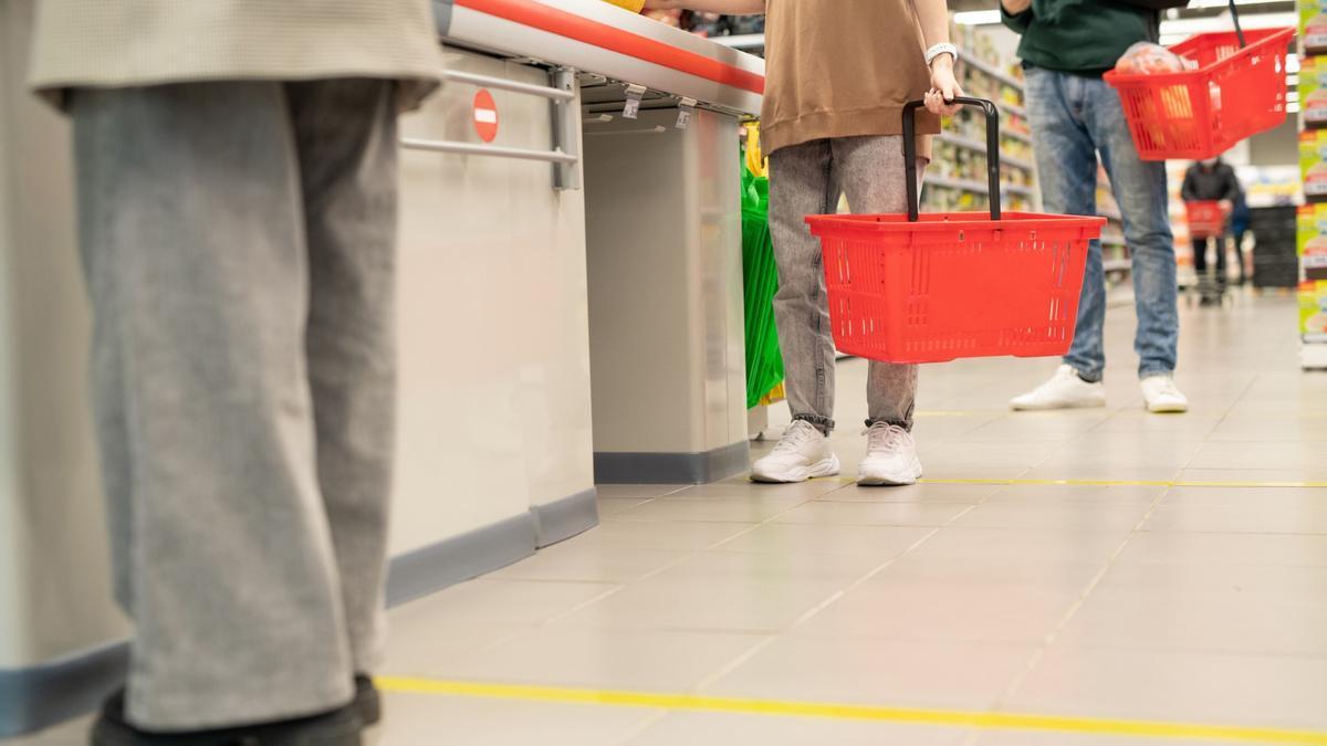 Varias personas esperan para pagar en la caja en un supermercado.