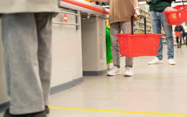 Varias personas esperan para pagar en la caja en un supermercado.