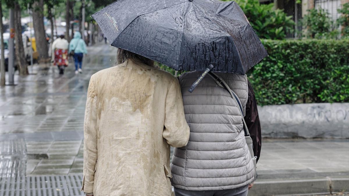 Dos personas pasean bajo la lluvia.