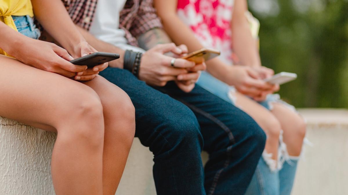 Personas mirando a la pantalla de su teléfono móvil.