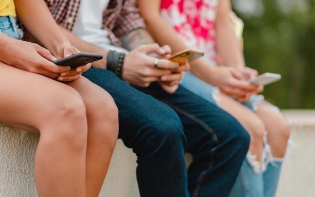 Personas mirando a la pantalla de su teléfono móvil.