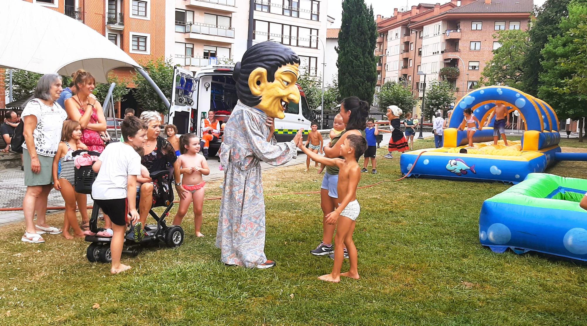 Un cabezudo saludando a una familia junto a los hinchables acuáticos