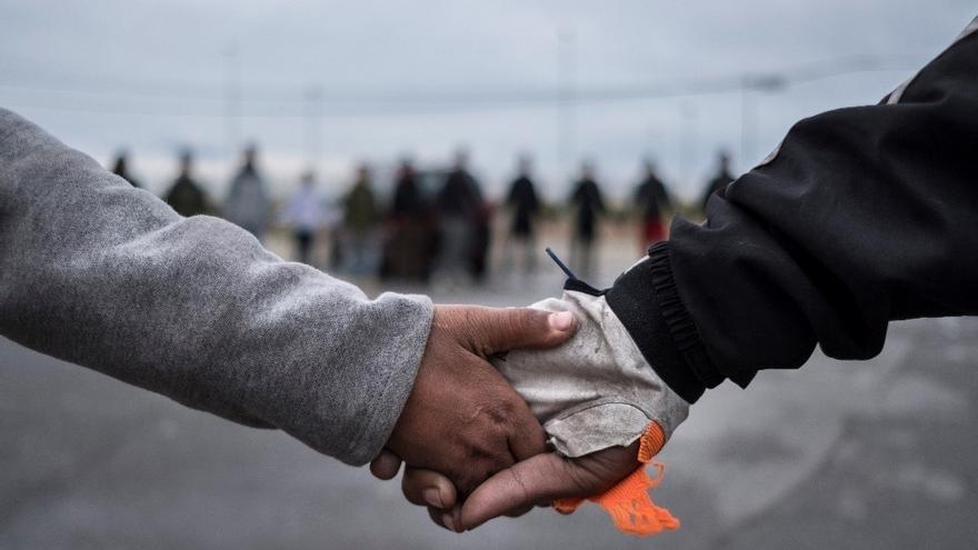 Dos menores migrantes se cogen de la mano.