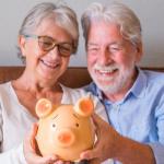 Una pareja de jubilados contempla una hucha con ahorros.