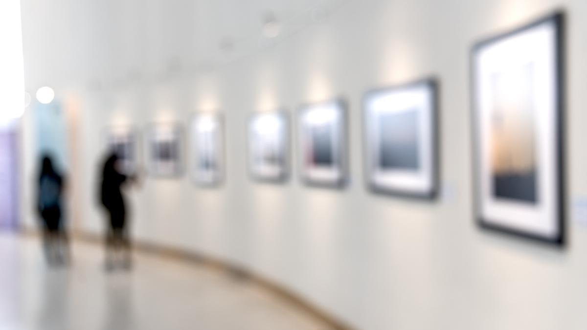 Dos personas observan cuadros en un museo.