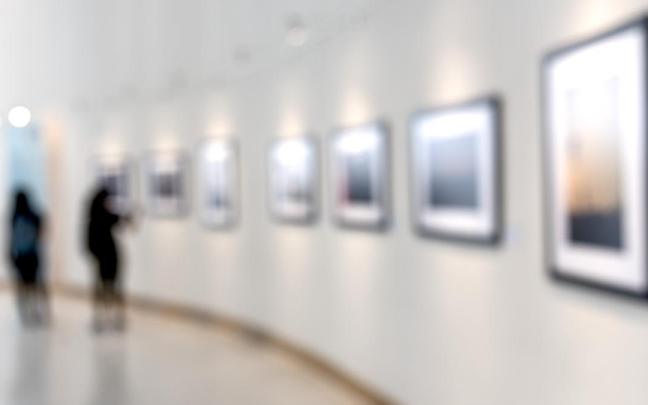 Dos personas observan cuadros en un museo.