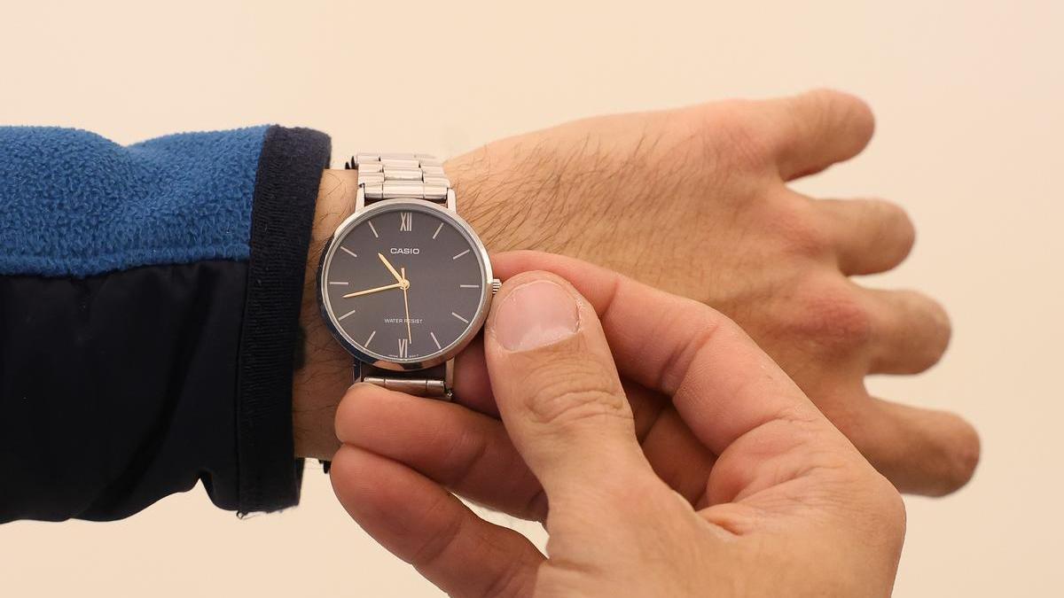 Un hombre cambia la hora en su reloj.