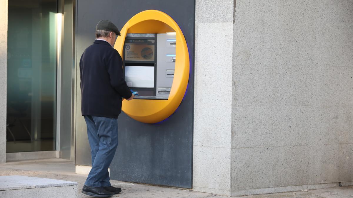 Un hombre saca dinero en un cajero automático.