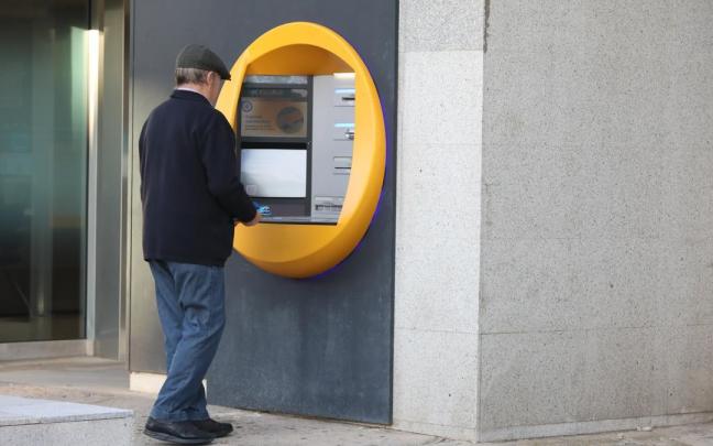 Un hombre saca dinero en un cajero automático.