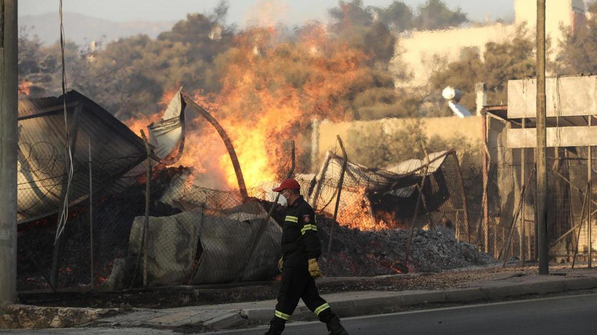 Un bombero pasa ante un establecimiento engullido por las llamas en Penteli, al norte de Atenas.