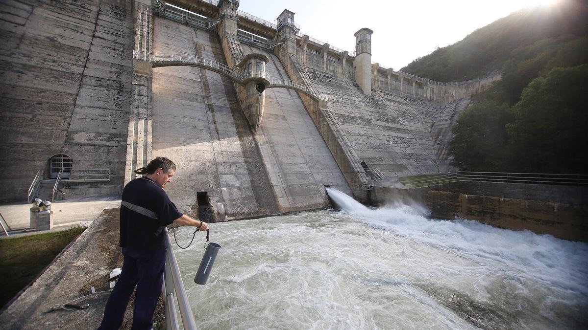 Un técnico coge una muestra de agua al pie de la presa durante la operación del desembalse llevada a cabo ayer.