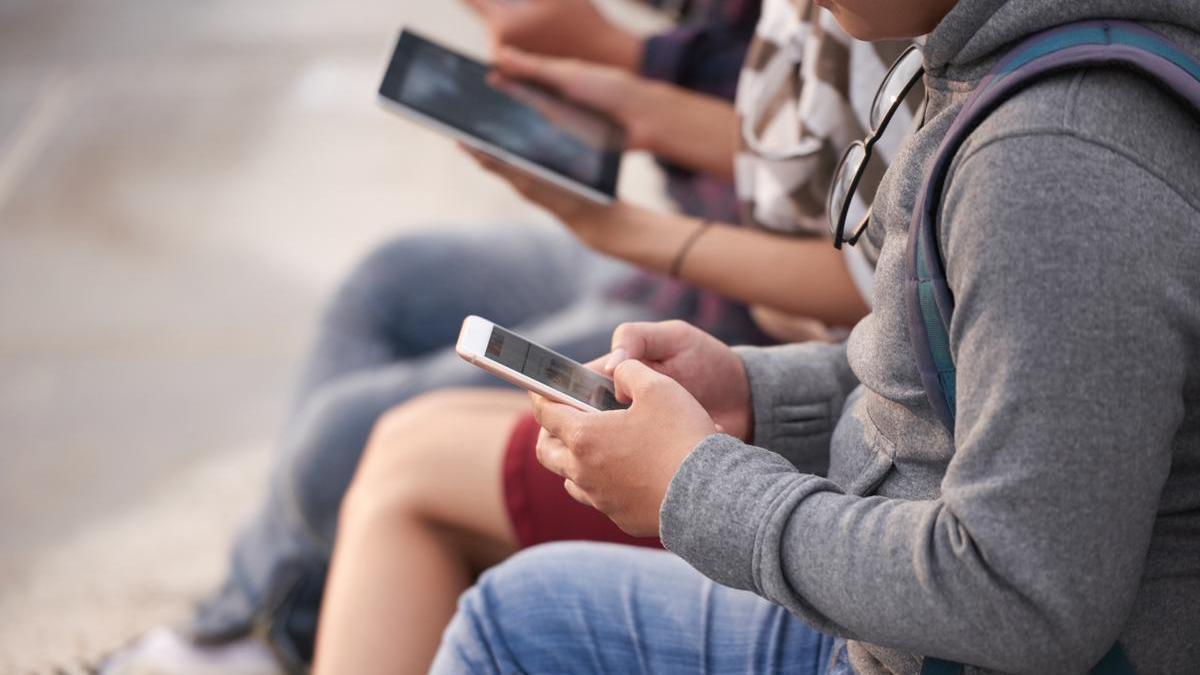 Varios jóvenes con dispositivos electrónicos.