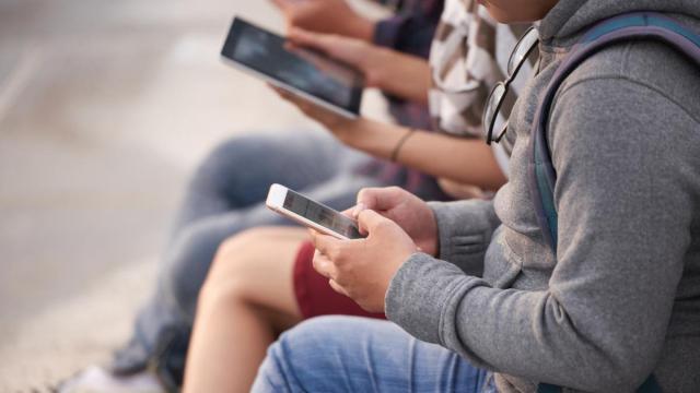 Varios jóvenes con dispositivos electrónicos.
