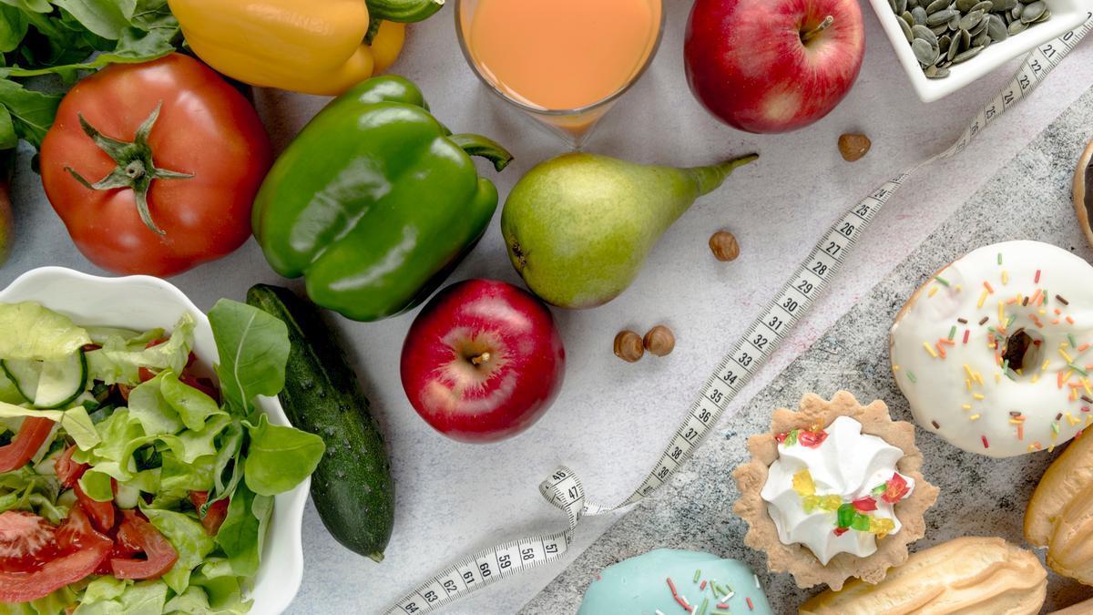 Una cinta métrica separa la comida saludable de los dulces.