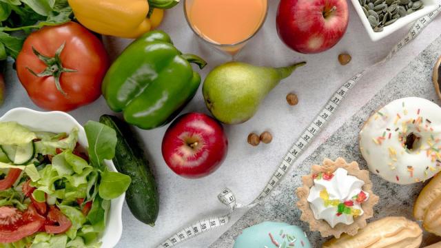 Una cinta métrica separa la comida saludable de los dulces.