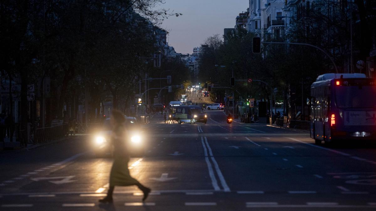 Una mujer cruza por un paso de cebra con la calle completamente oscura debido al apagón.
